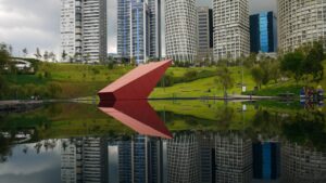red-umbrella-near-body-of-water-and-city-buildings