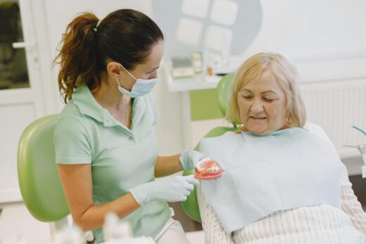 Dentist showing patient how to brush dentures