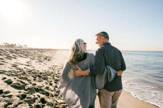 Senior couple enjoying a walk on a California beach, representing retirees exploring the best Medicare Advantage plans in California.