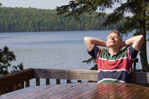 Early retiree relaxing outdoors on a lakeside deck, symbolizing peace of mind from securing health insurance before Medicare.